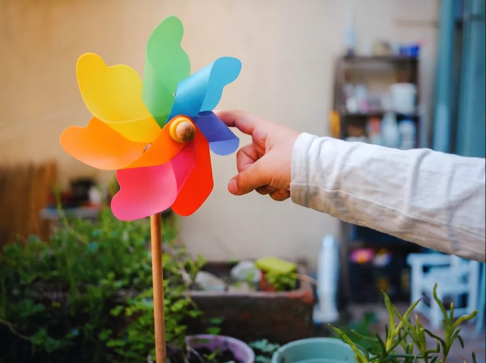 Niña jugando con un molinillo de papel de colores