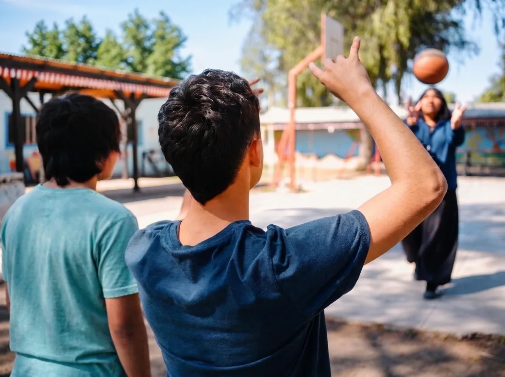 Adolescentes jugando al baloncesto en el patio de una escuela